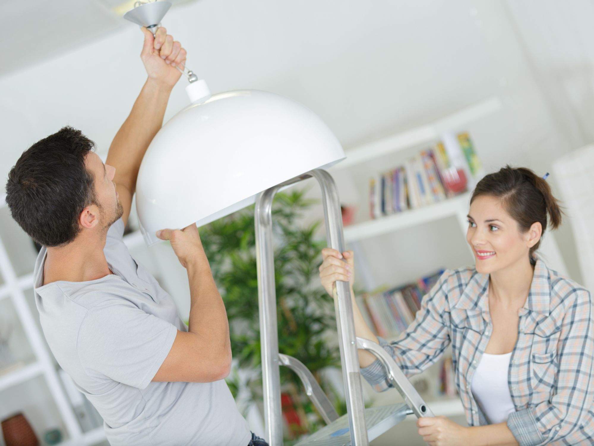 Nainen ja mies asentamassa lamppua kattoon.